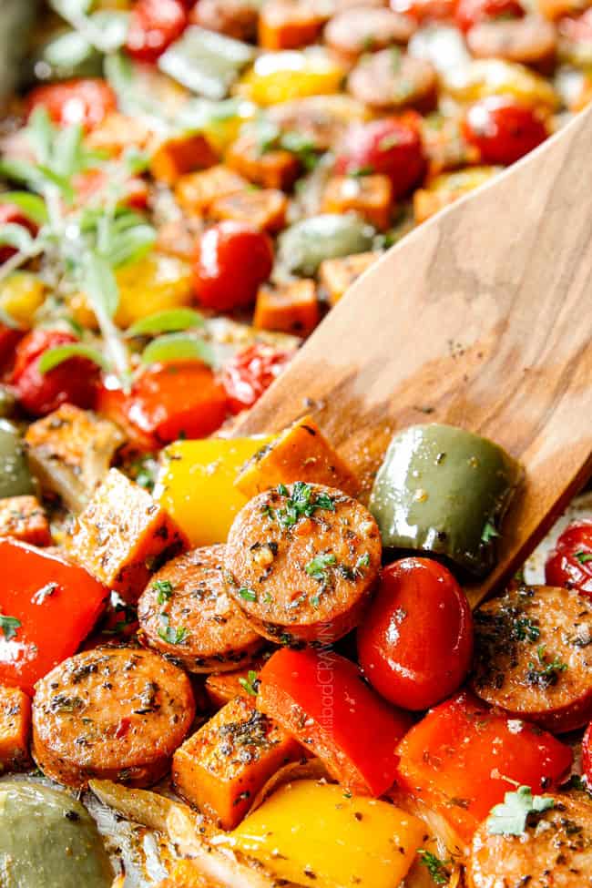 up close of Italian Sausage and Peppers being scooped up with a wooden spoon.