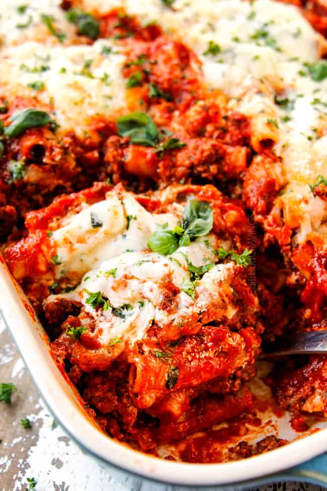 showing how to serve Baked Ziti recipe with ricotta and sausage with an up close of a spoonful of pasta in a 9x13 pan