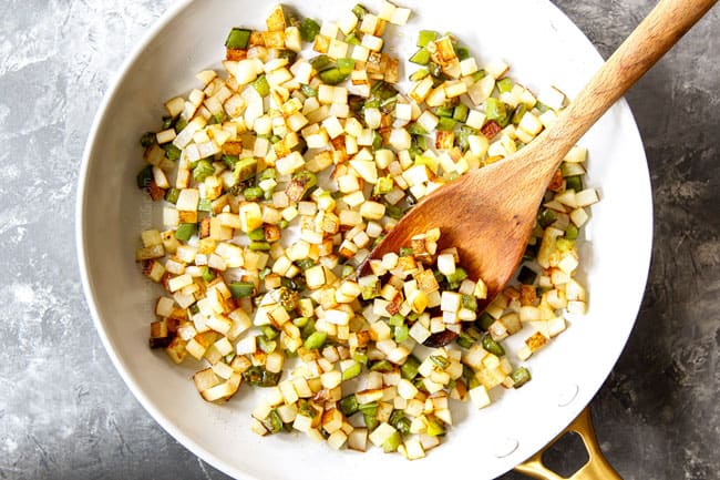 showing how to make breakfast tacos by cooking potatoes, onions and bell peppers in a skillet