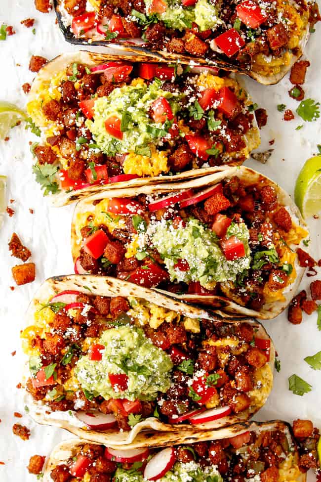 showing how to serve breakfast tacos by lining assembled tacos in a row on a white tray