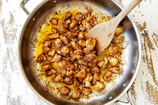 showing how to make Green Chili Chicken by cooking chicken seasoned with chili powder, cumin, smokes paprika, cayenne pepper, salt and pepper in a large stainless steel skillet