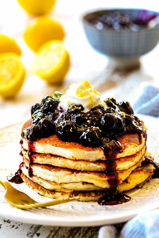 showing to serve lemon ricotta pancakes recipe by stacking pancakes on a white plate and topping with syrup