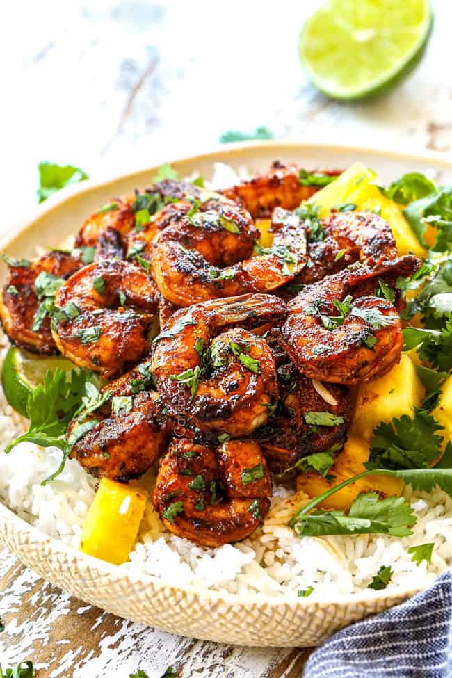 showing how to serve jerk shrimp by piling shrimp on rice and pineapple
