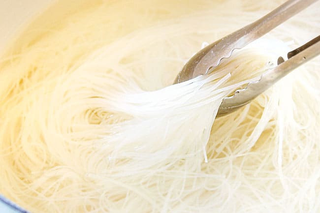 showing how to make pho by soaking rice noodles in hot water until tender