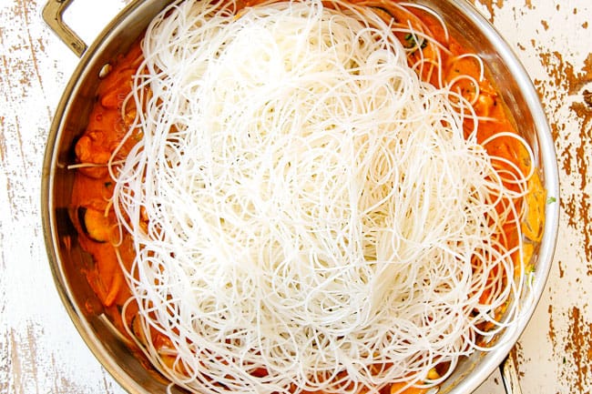 showing how to make rice noodles recipe by adding rice noodles to coconut curry sauce
