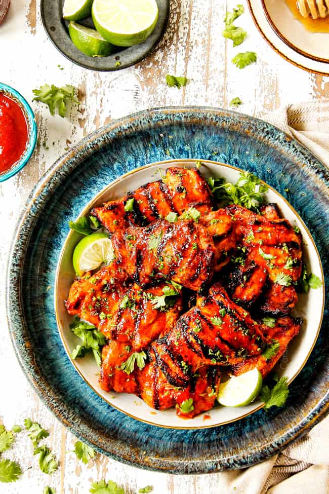 top view showing how to serve Honey Sriracha Chicken on a plate surrounded by limes, honey and sriracha