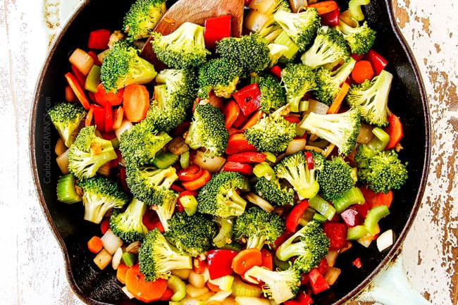showing how to make Hunan chicken by adding broccoli, carrots, celery, carrots, bell peppers and chili peppers to skillet