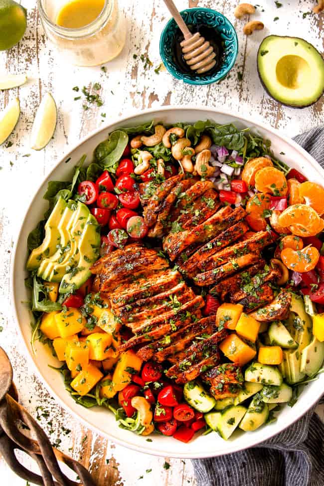 showing how to make mango salad with a top view of salad in a white bowl and garnishing with cilantro