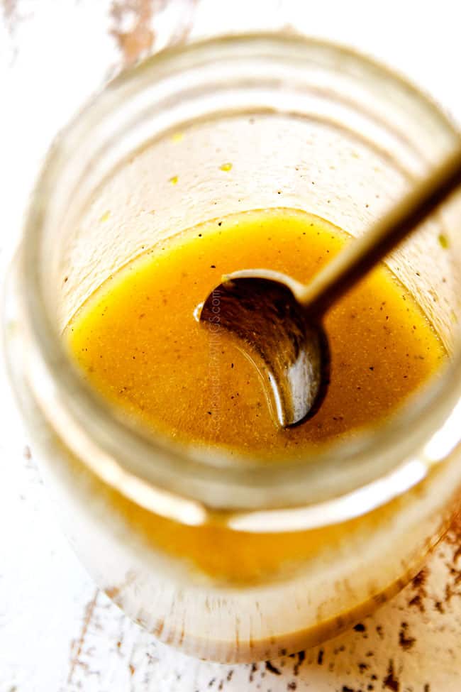 showing how to make mango salad by whisking mango salad ingredients together in a glass jar