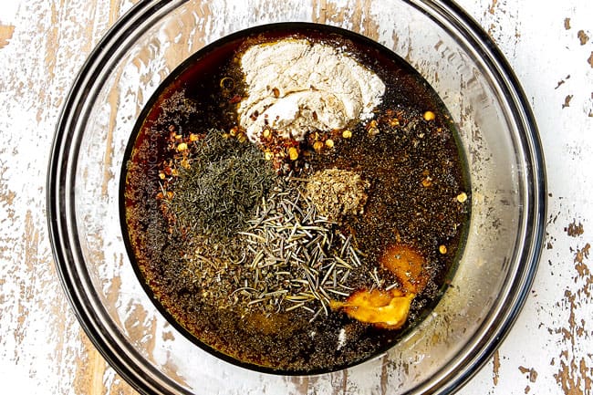 showing how to make steak kabobs by whisking together the steak marinade ingredients: soy sauce, balsamic, lemon juice, olive oil and seasonings in a glass bowl