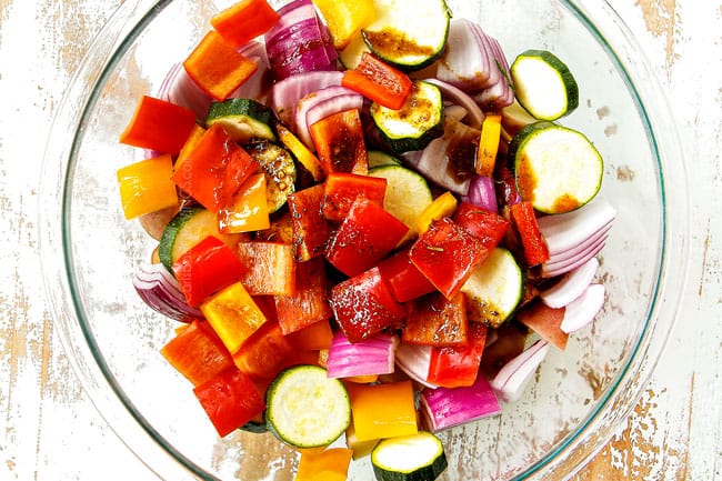 showing how to make steak kabobs by adding chopped potatoes, bell peppers, onions, zucchini to a glass bowl with 3 tablespoons of reserved steak marinade