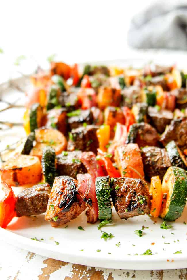 up close of steak kabobs on a white platter showing how juicy they are
