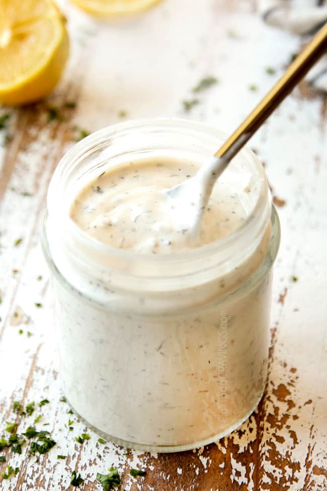 showing how to make steak salad by stirring blue cheese dressing in a glass jar with a gold spoon