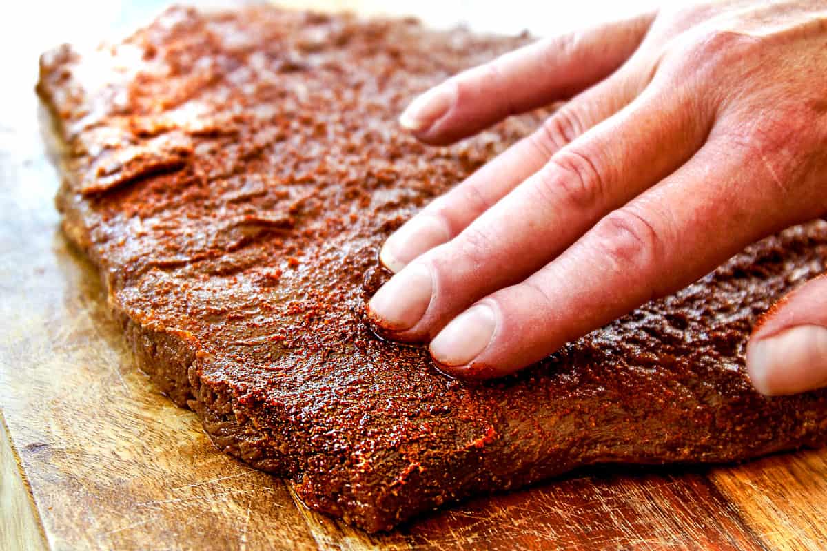 showing how to make carne asada by massaging a rub all over steak