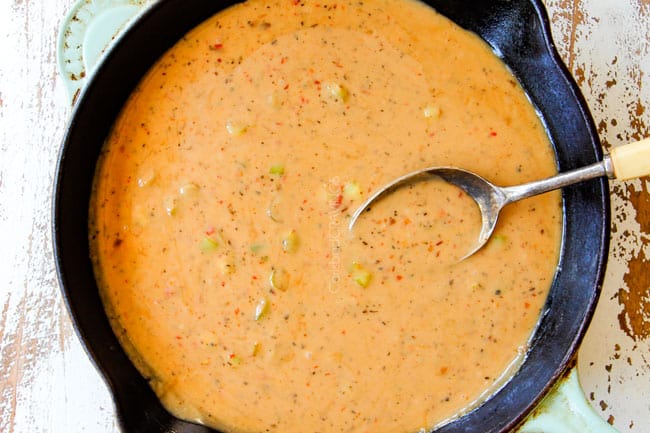 showing how to make coconut chicken recipe by simmering sauce in a cast iron skillet until thickened