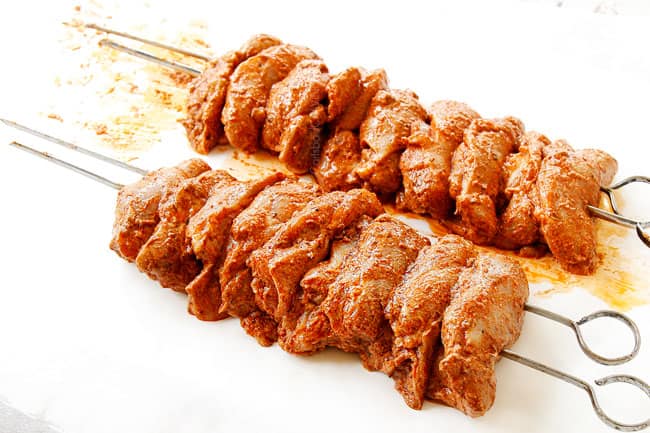 showing how to make doner kebab by threading chicken onto skewers