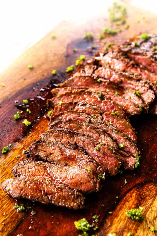 marinated flank steak on a cutting board cut into thin strips showing how juicy it is