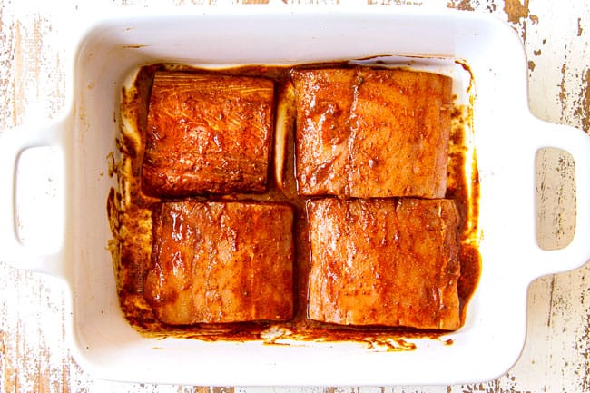 showing how to make mahi mahi fish tacos by marinating in a white dish