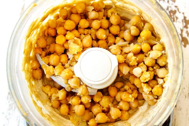 showing how to make hummus by adding chickpeas to food processor