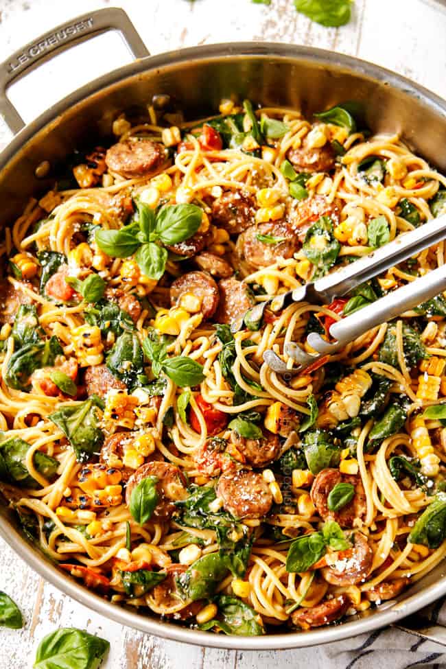 showing how to make spinach pasta recipe by adding Parmesan to the pasta in stainless steel skillet