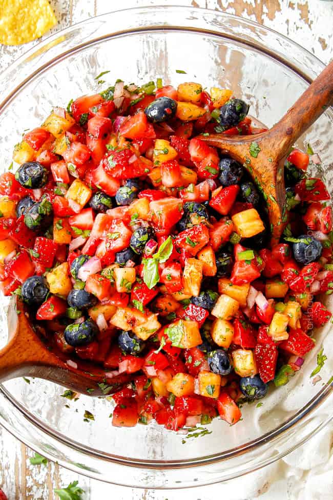 top view of strawberry salsa in a glas bowl with strawberries, cilantro, red onions and cilantro