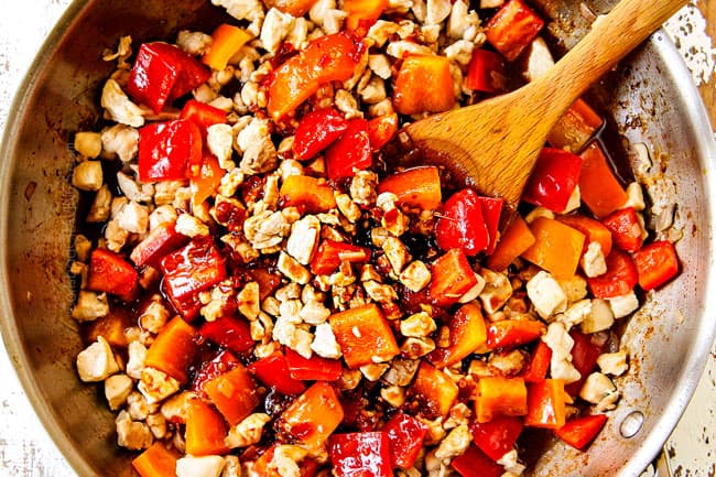 showing how to make Thai basil chicken by adding the stir fry sauce to the chicken and bell peppers in a stainless steel skillet