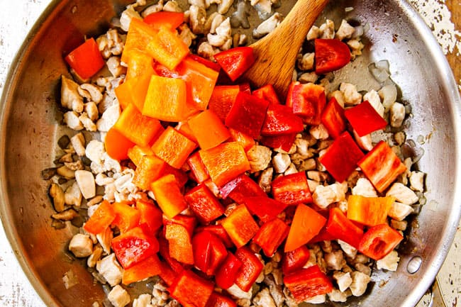 showing how to make basil chicken by stir frying bell peppers, garlic and ginger with the chicken
