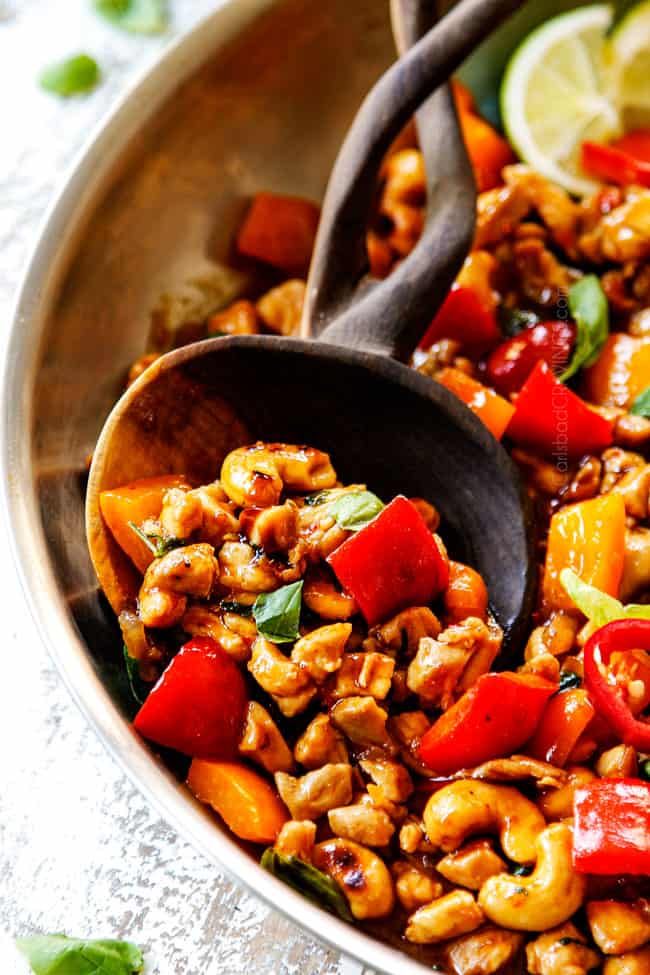 up close of Thai Basil Chicken in a wooden spoon showing the texture of the chicken
