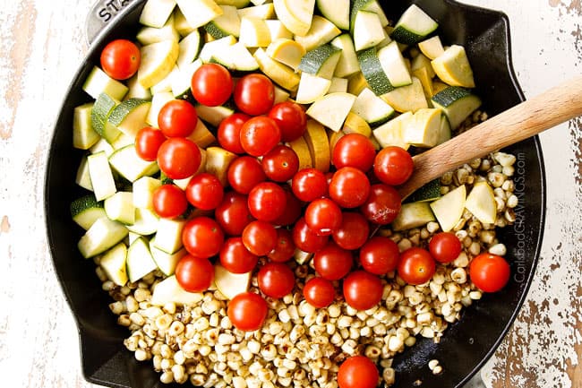 showing how to make Tuscan Chicken by adding zucchini, squash and cherry tomatoes to the cast iron skillet