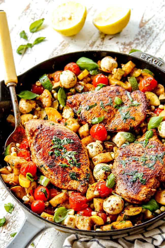 serving Tuscan Chicken recipe with a big spoonful of veggies and chicken in a cast iron skillet