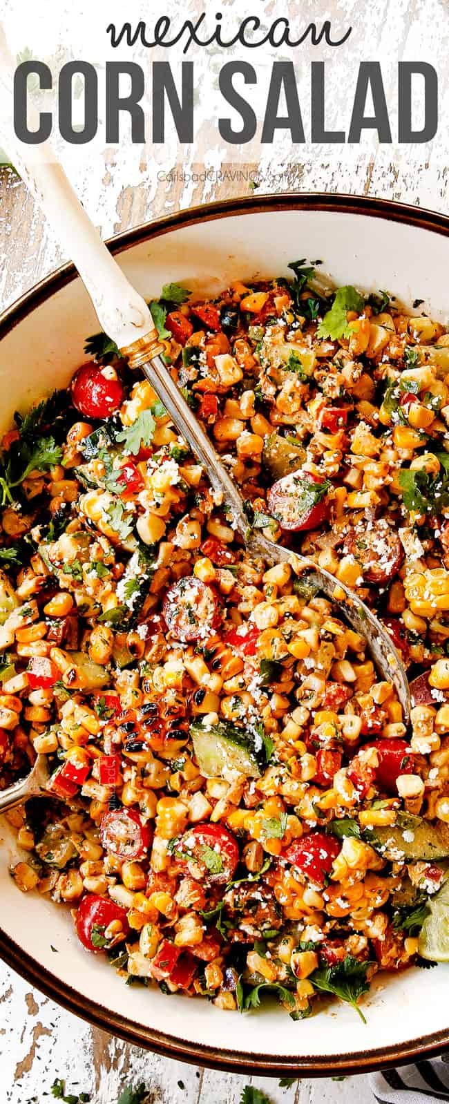 top view of esquites (Mexican street corn Salad) in a white bowl with two serving spoons
