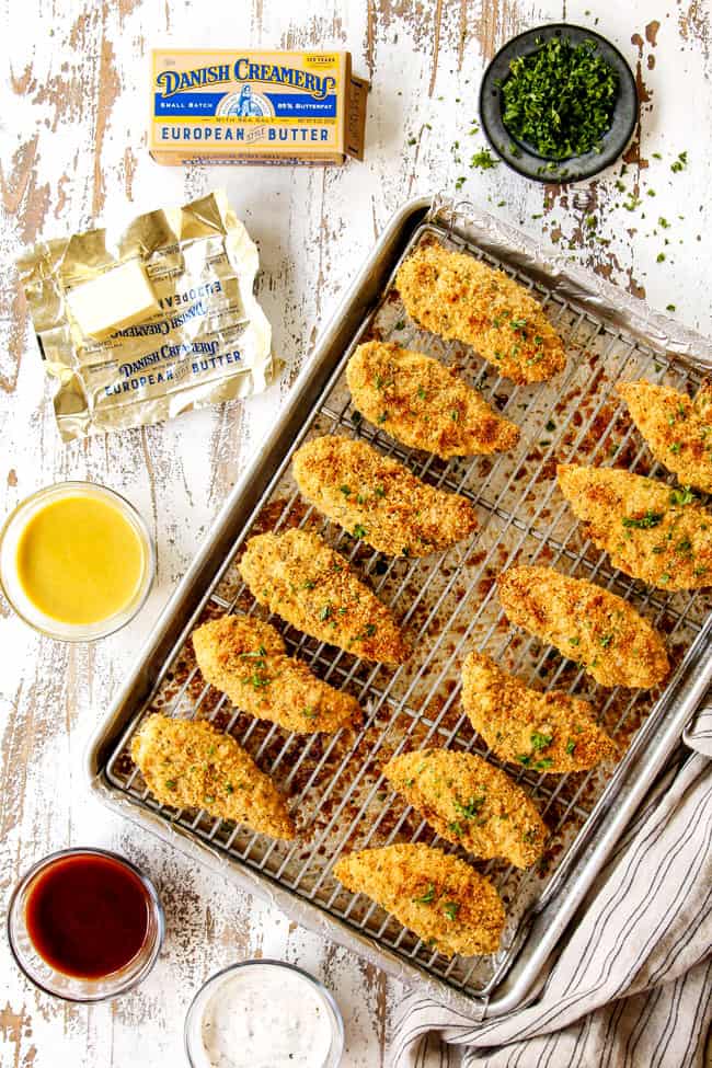 showing what to serve with baked Parmesan crusted chicken with bowls of honey mustard dip, barbecue sauce and ranch next to chicken on a baking tray