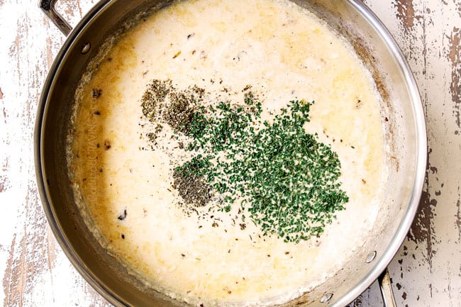 showing how to make pasta primavera recipe by adding heavy cream, chicken broth, parsley, oregano, thyme and red pepper flakes to a stainless steal skillet to make cream saucee