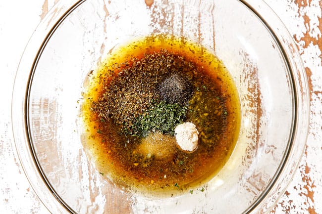 top view showing how to make pesto pasta salad recipe by adding olive oil, lemon juice, garlic and herbs to a glass bowl