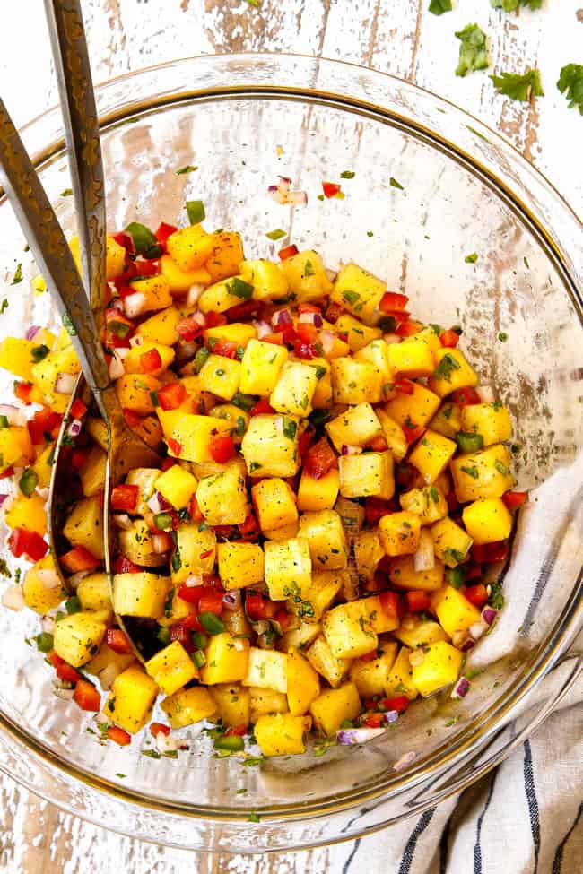 showing how to make steak taco recipe by mixing pineapple salsa ingredients in a glass bowl