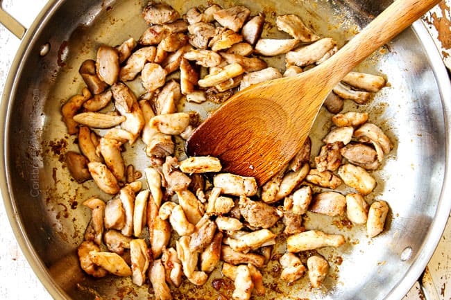showing how to make chicken yakisoba by cooking chicken in a large stainless steel pan