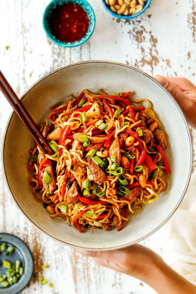 top view of chicken yakisoba in a white bowl garnished with green onions