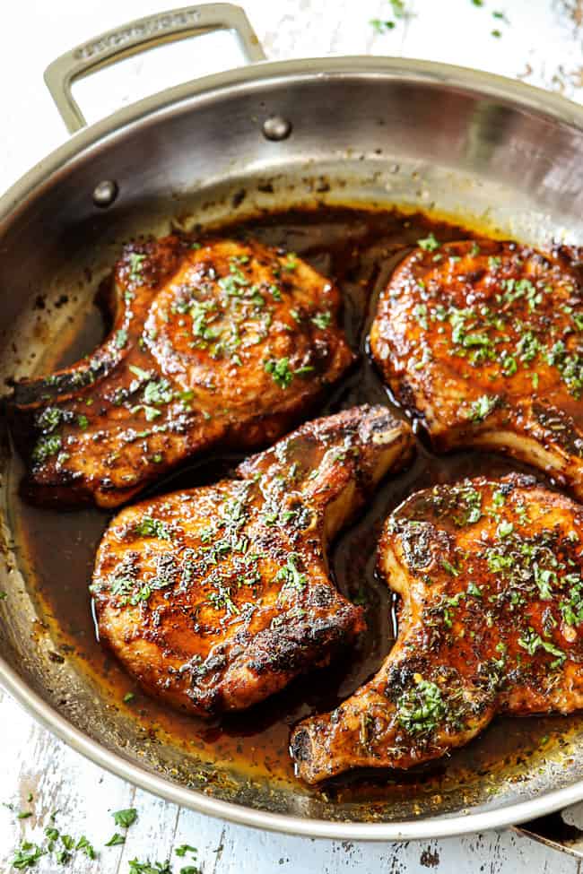 side view of brown sugar pork chops in a stainless steel skillet garnished with parsley