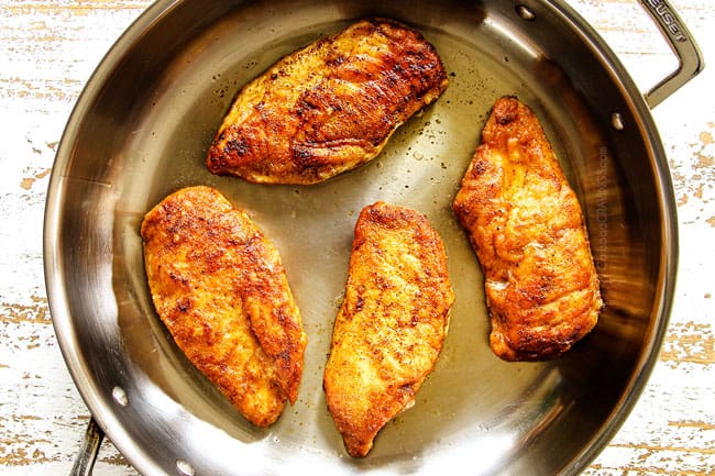 showing how to make creamy Tuscan chicken by cooking chicken cutlets until golden in a stainless steel pan