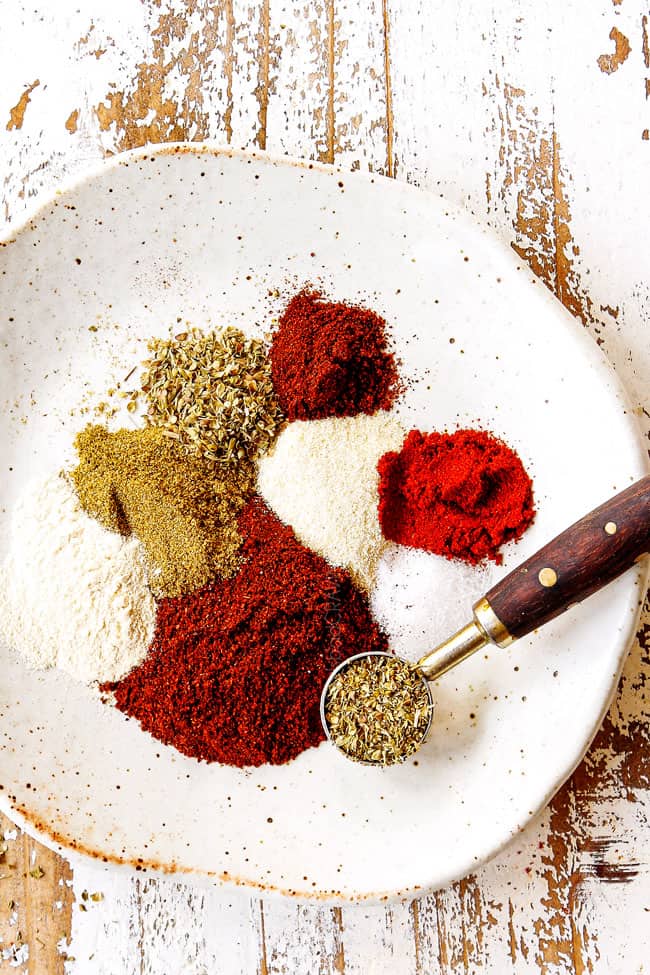 top view showing how to make fajita seasoning recipe by adding chili powder, ground cumin, smoked paprika, garlic powder, onion powder, salt, pepper and cayenne pepper to a tan dish.