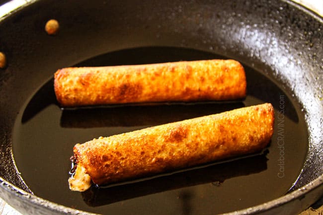 showing how to make flautas by frying flautas in a black skillet