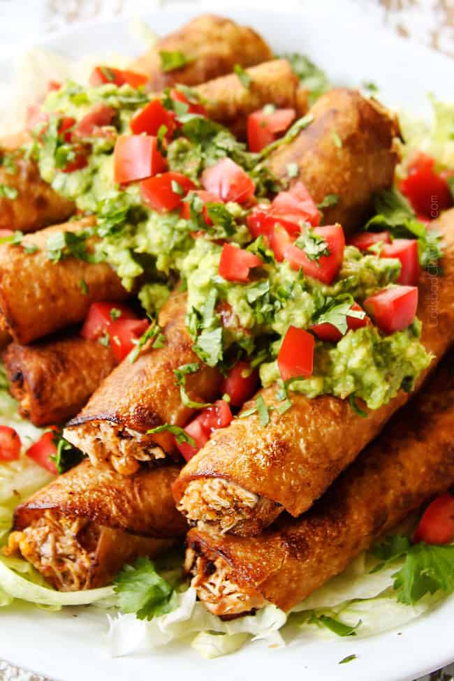 up close of flautas on a white plate with cheesy chicken come out the ends of the flautas