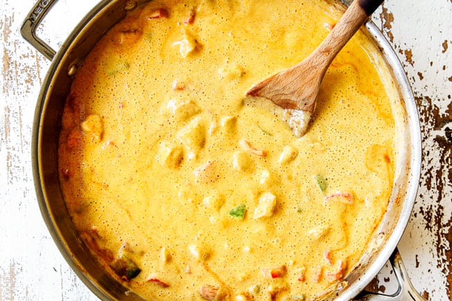 showing how to make mango chicken by adding mango blender sauce to stainless steel skillet