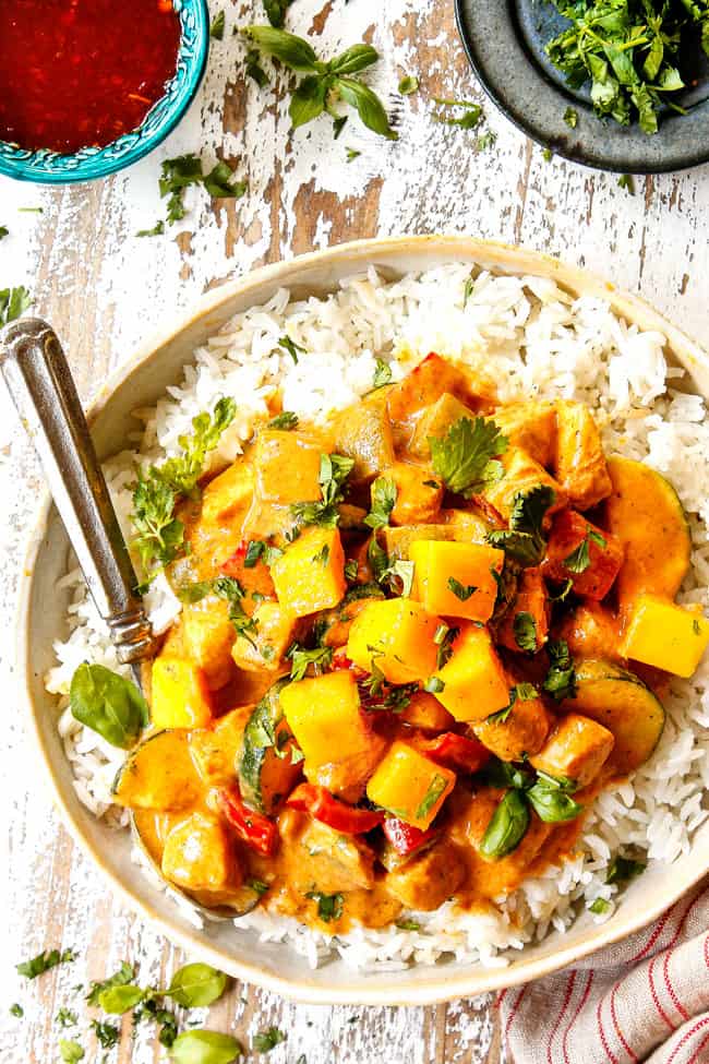 top view of mango chicken curry in a tan bowl with white rice garnished with cilantro