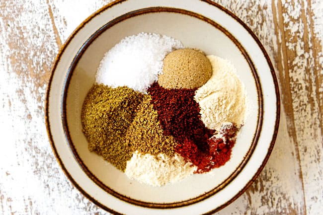 showing how to make steak and potatoes recipe by adding kosher salt, pepper, cumin, chili powder, coriander, paprika to a small tan bowl