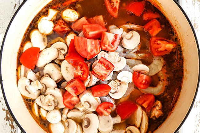 showing how to make Thai Tom Yum Soup recipe by adding shrimp, tomatoes and mushrooms to the soup pot