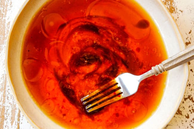 showing how to cook bok choy by whisking soy sauce, sesame oil, ginger and garlic together in a cream bowl