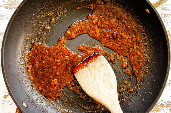 showing how to cook bok choy by simmering sauce in a black nonstick skillet