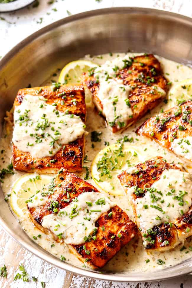 mahi mahi fish in a stainless steel skillet with lemon cream sauce garnished by chives