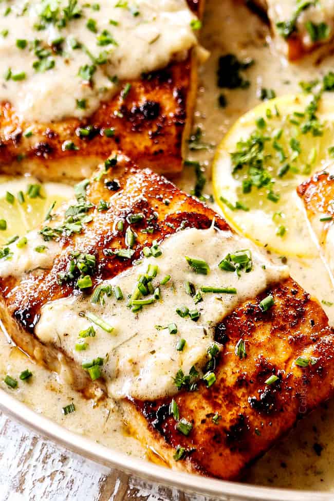 up close of mahi mahi fish garnished with parsley and chives in lemon cream sauce
